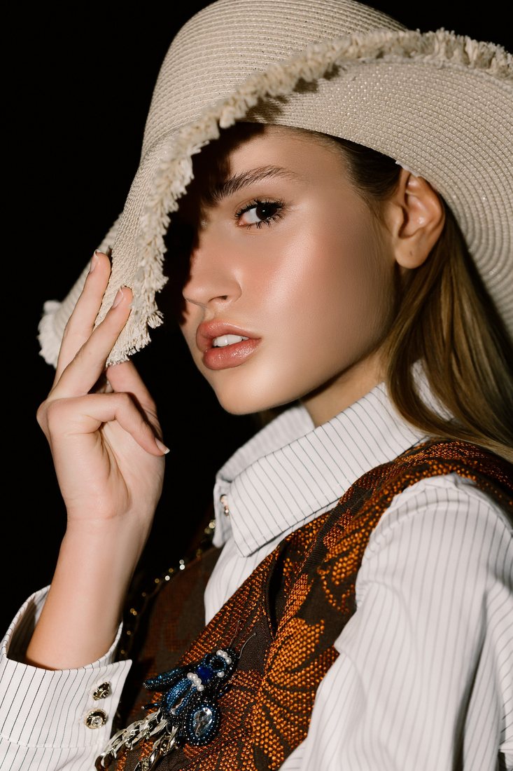Close-up fashion portrait of a woman wearing a wide-brimmed hat.