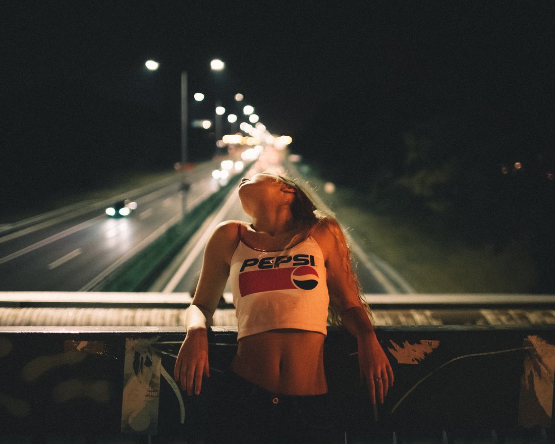 A night portrait beside a road with blurred headlights in the background.