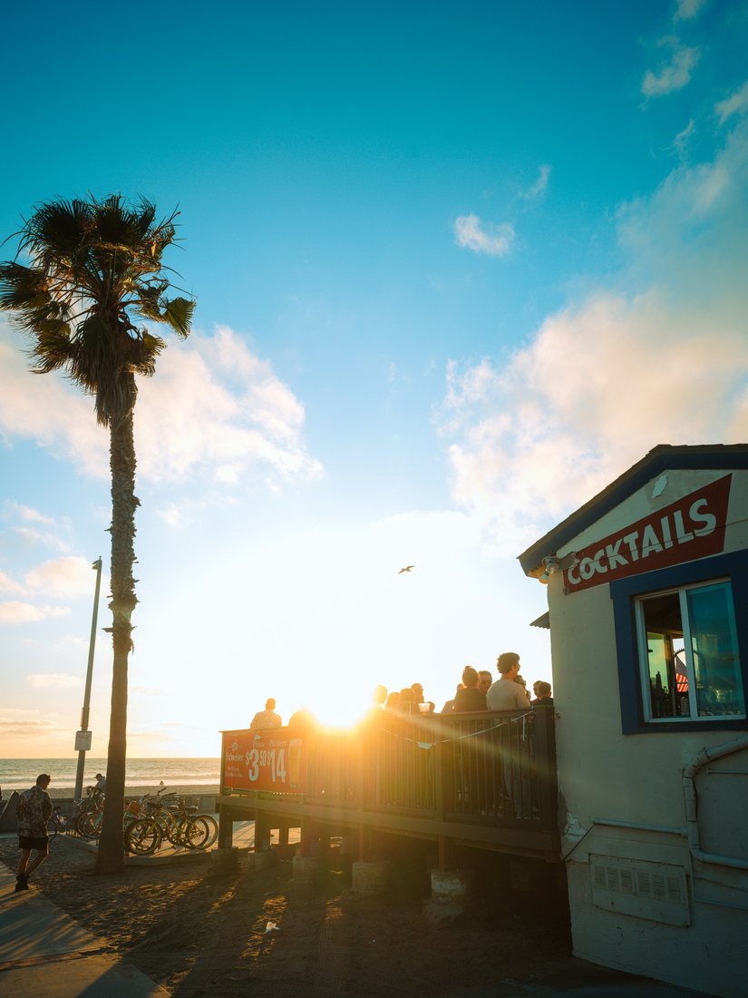 Sunset beside a beachside terrace and a tall palm tree.