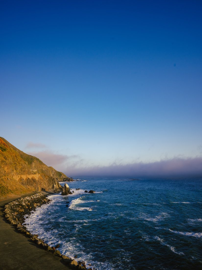 A coastline curves beside deep blue ocean water.