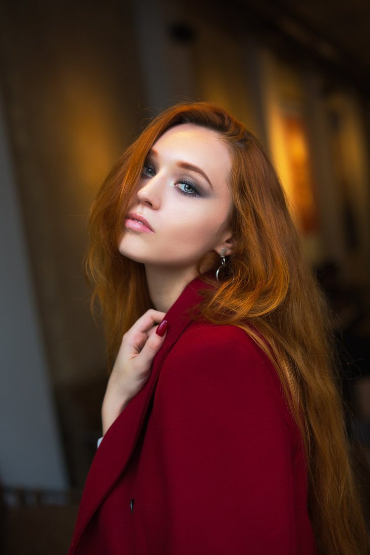 Portrait of a red-haired woman in a burgundy top against a softly blurred background.