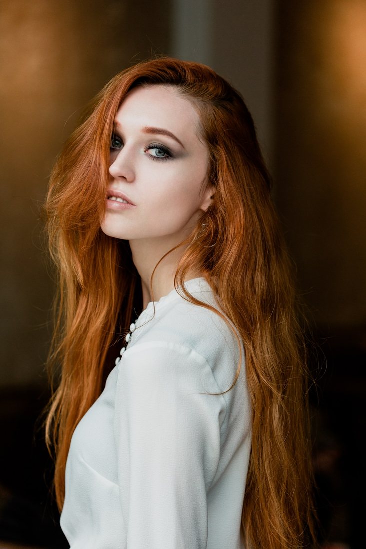 Portrait of a red-haired woman wearing a white blouse.