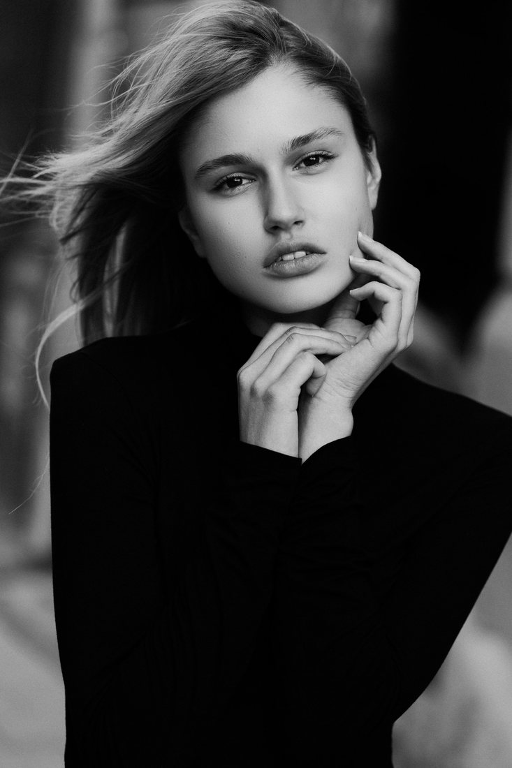 Black-and-white portrait of a woman resting her hands near her face.