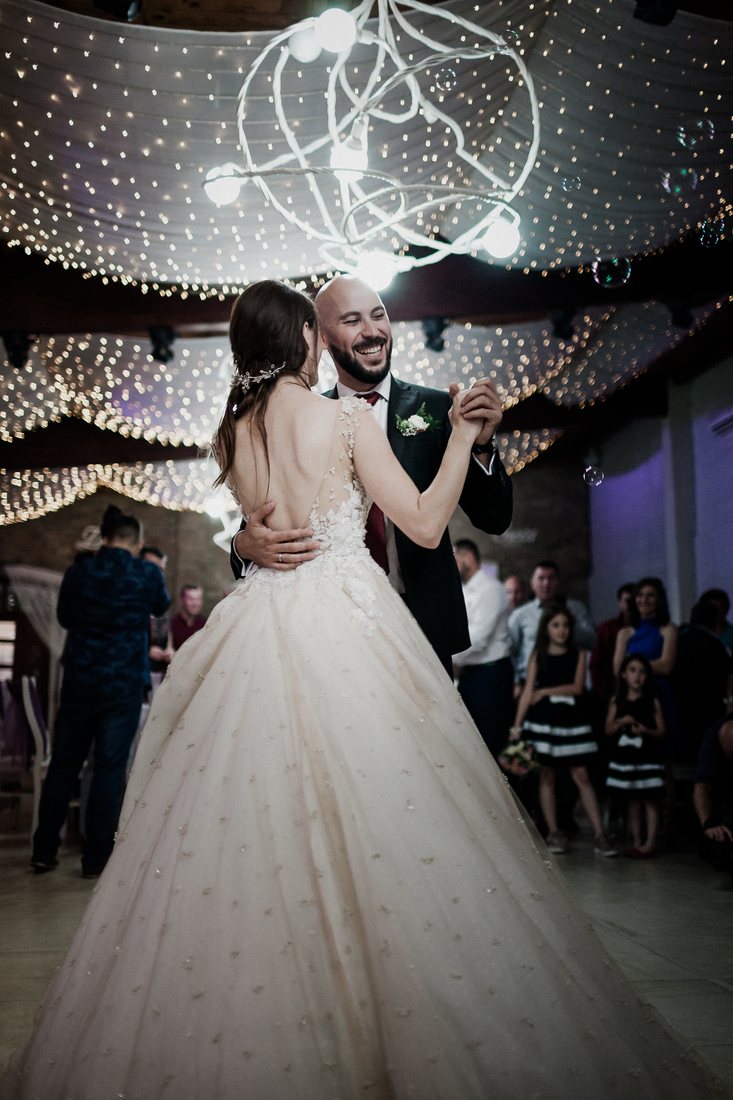 A bride and groom dance beneath glowing lights at their wedding reception.